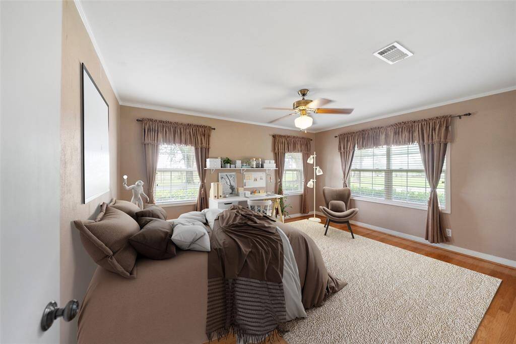 Virtually staged to show off this roomy guest bedroom—featuring hardwood floors and serene views of the surrounding property.