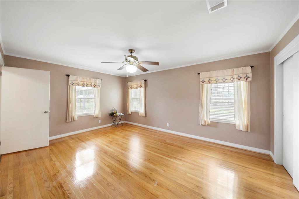 Spacious and light-filled, this secondary bedroom features hardwood floors, ceiling fan, and multiple windows with peaceful views.