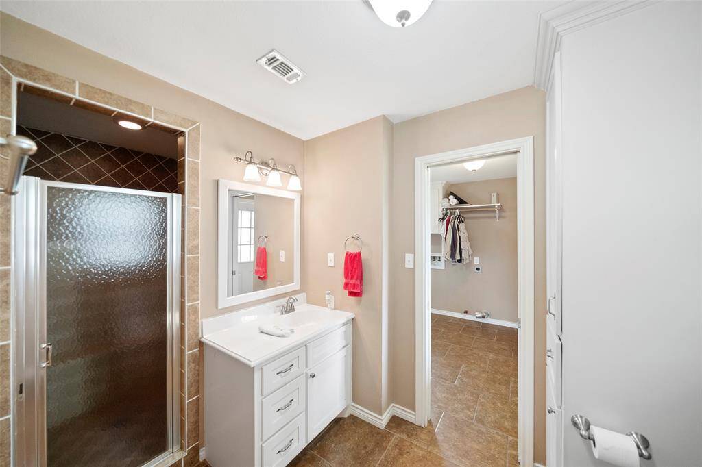 Second full bath includes a walk-in tiled shower, updated lighting, and direct access to the laundry room for added functionality.