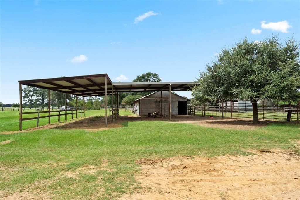 Spacious metal overhang and adjacent barn offer flexible shelter for horses or equipment.