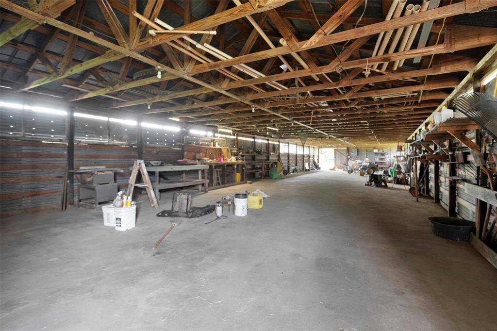 Expansive barn with concrete floor and shelving provides ample space for equipment storage and farm projects—tools and machinery not included in lease.
