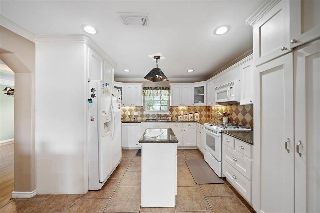 Bright and functional kitchen with granite countertops, classic white cabinetry, and a gas cooktop—perfect for everyday meals or weekend gatherings.