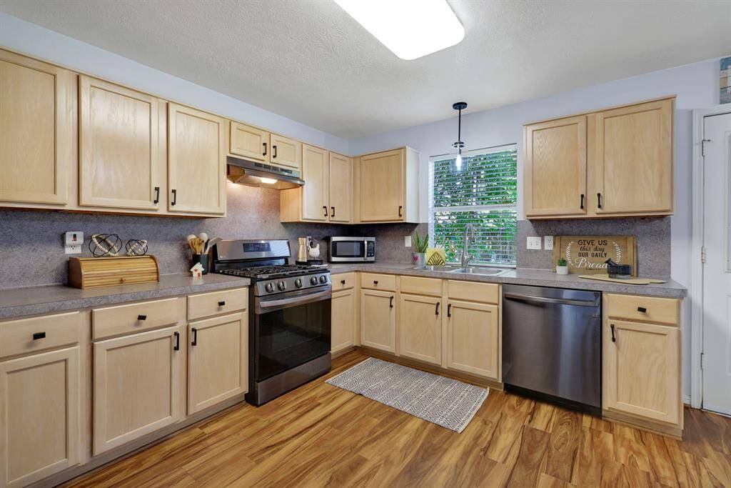 This kitchen features light wood cabinetry, stainless steel appliances, and a cozy layout. It has ample counter space, a gas stove, and a window above the sink for natural light.