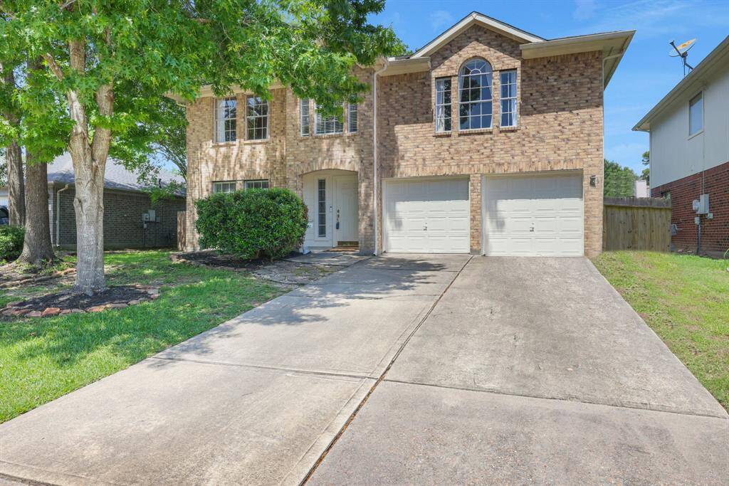 Welcome Home!! This two-story brick house with a double garage and a large driveway, surrounded by a well-maintained lawn and mature trees, creating a welcoming and shaded front yard.
