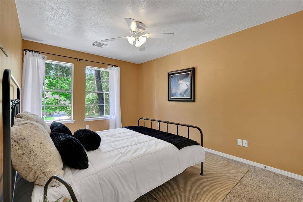 This bedroom features warm-toned walls and a large window that provides natural light and views,.