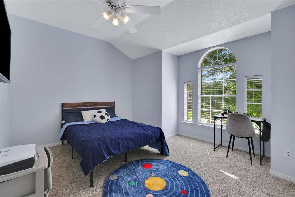 Spacious bedroom with a vaulted ceiling, featuring a large arched window that offers plenty of natural light.