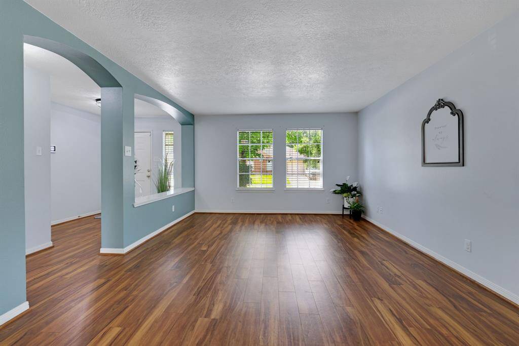 This inviting living space features sleek vinyl plank floors and ample natural light from large windows. An open archway design adds architectural interest.  Perfect for modern living.