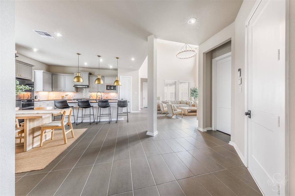 The open-concept design offers seamless views into the family room, dining area, and gourmet kitchen. Neutral tones, sleek tile floors, and soaring ceilings create a fresh and spacious feel throughout.