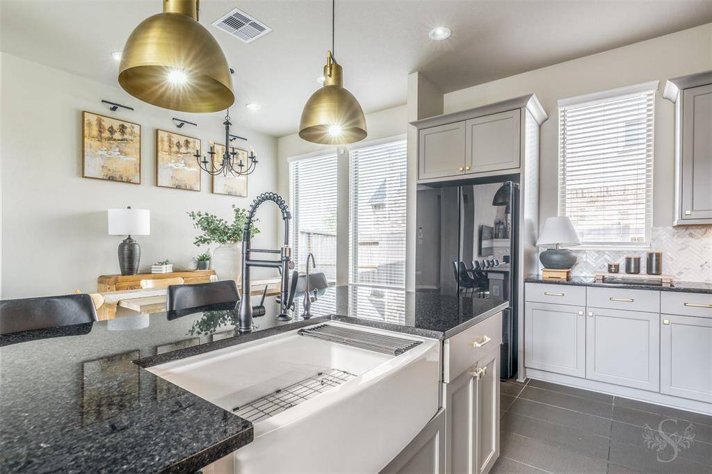 The gourmet kitchen offers many upgrades including a farmhouse sink with faucet, pendant lighting, cabinet handles/knobs, pullout kitchen cabinet organizer and soft close cabinets. Ample natural light enhances the bright and airy atmosphere.