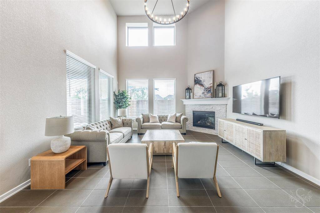 Light-filled family room with soaring ceilings, upgraded modern chandelier, cozy fireplace and a wall of windows overlooking the backyard. Designed for comfort, connection, and relaxed everyday living.