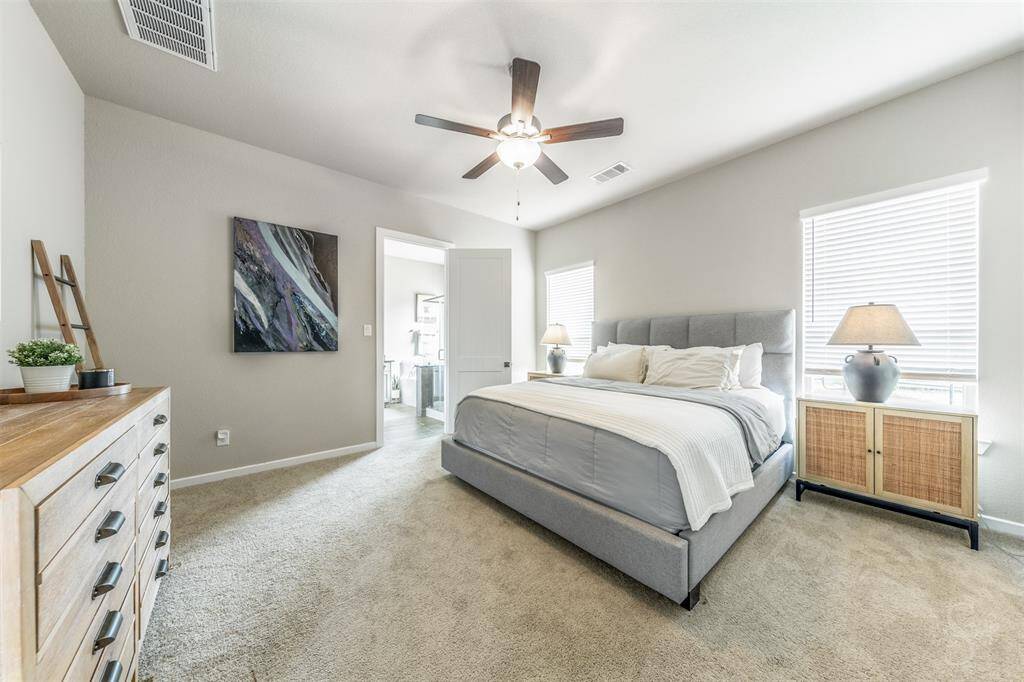 Spacious primary bedroom retreat with soft natural light, neutral carpet, and high ceiling. A serene space designed for rest and relaxation. There's plenty of room for a king size bed and a sitting area.