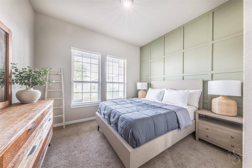 Charming secondary bedroom featuring large windows with custom blinds, plush carpeting, walk-in closet and a stylish accent wall. Bright and welcoming, perfect for guests or family.