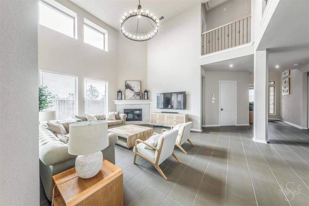 Light-filled family room with soaring ceilings, upgraded modern chandelier, cozy fireplace and a wall of windows overlooking the backyard. Designed for comfort, connection, and relaxed everyday living.