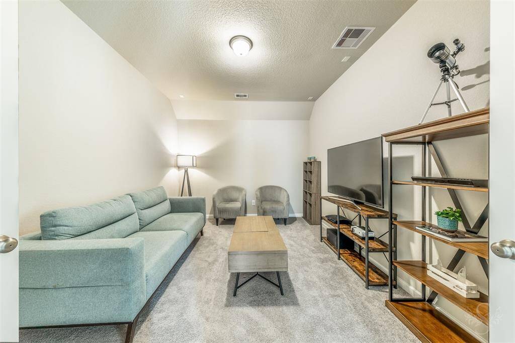 Cozy prewired media room featuring soft carpeting, high angled ceiling, neutral tones, and a quiet atmosphere ideal for movie nights or sports viewing. A perfect retreat for entertainment and family time.