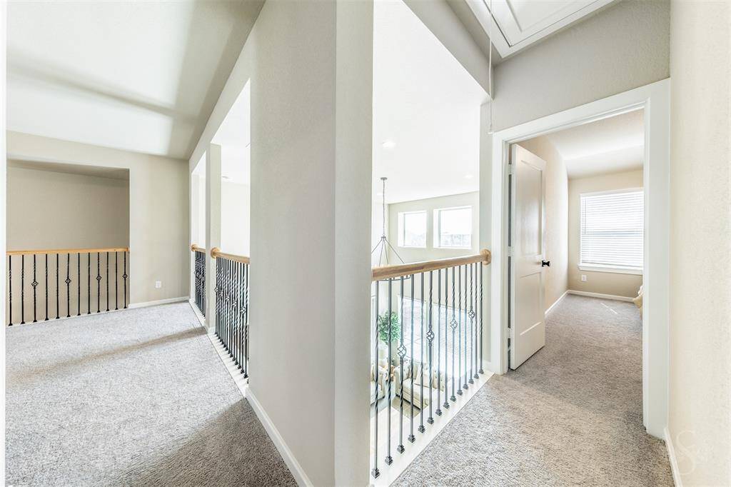 Upstairs hallway with elegant wrought iron balusters and views into the family room below. An open and airy transition space connecting bedrooms and living areas.