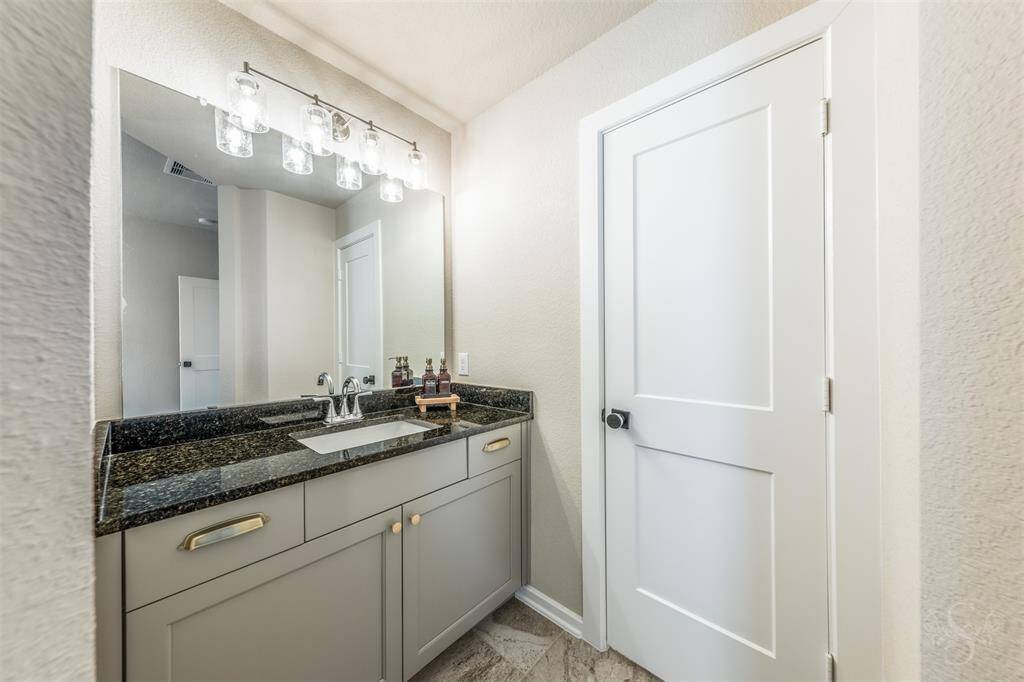 Secondary bathroom with granite counter, updated lighting, and a spacious vanity. Fresh, stylish, and designed for everyday convenience.