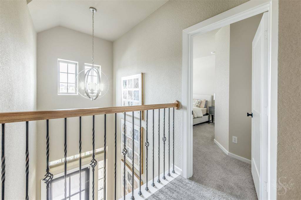 Charming landing upstairs with views of the grand two-story entry and upgraded modern chandelier. Elegant wrought iron spindles add architectural interest and style.