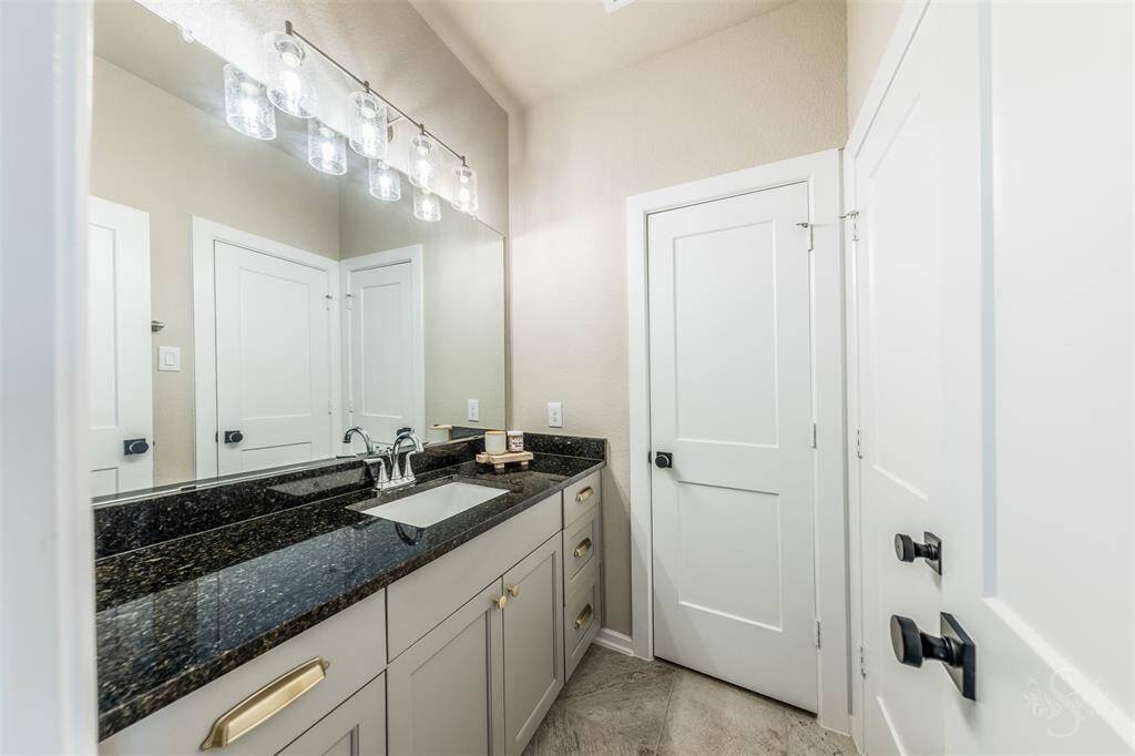 Stylish secondary bathroom offering granite countertops, updated fixtures, and a tub/shower combo with tilesurround.
