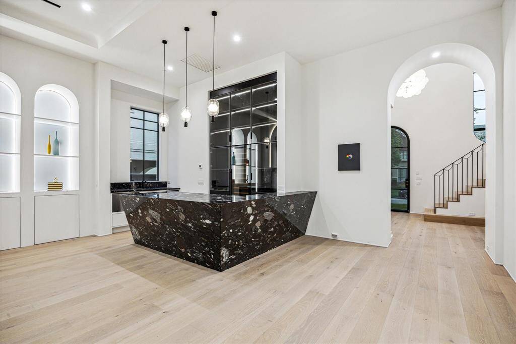 The focal anchor of the expansive downstairs living area is the wet bar fabricated from striking Brazilian Quartzite, a natural stone, with Galaxy coloration.