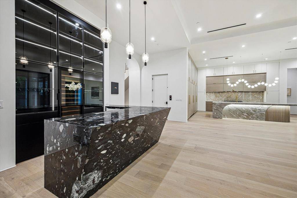 The bar uses smoked glass and internal lighting to create an especially handsome look. The central piece is the tall wine storage cooler. It is flanked by two more wine closets.