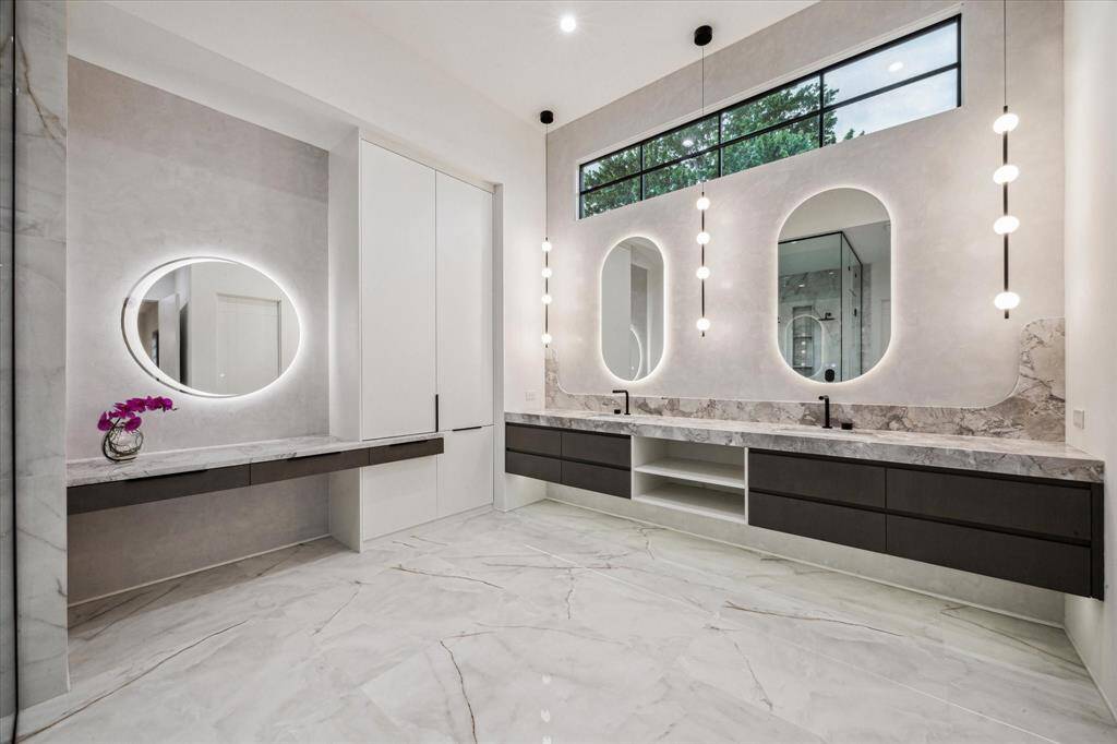 Internally lit custom-made mirrors seduce the eye and frame the Primary Bath with its Venetian Plaster walls and floating cabinetry.
