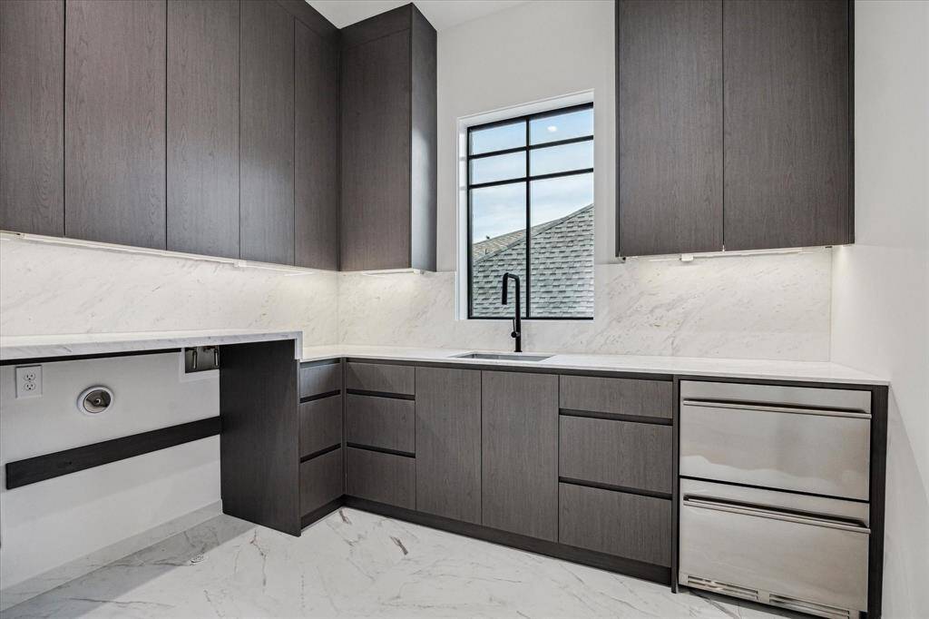 Clean and sophisticated design even carries on into the upstairs Laundry Room: Calcutta white marble counters,  two refrigeration drawers and plenty of storage.