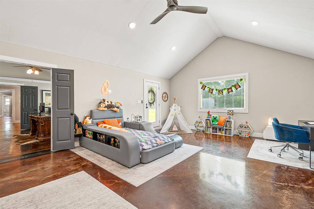 This spacious, bright room features high ceilings, polished concrete floors, and ample natural light. Ideal for a child's bedroom or playroom. The neutral tones create a welcoming atmosphere.