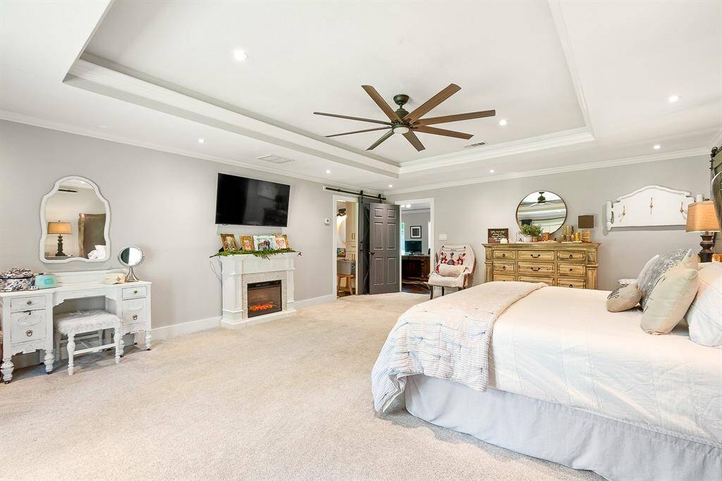 This spacious primary bedroom features a tray ceiling with recessed lighting and a ceiling fan offering a comfortable and inviting atmosphere.