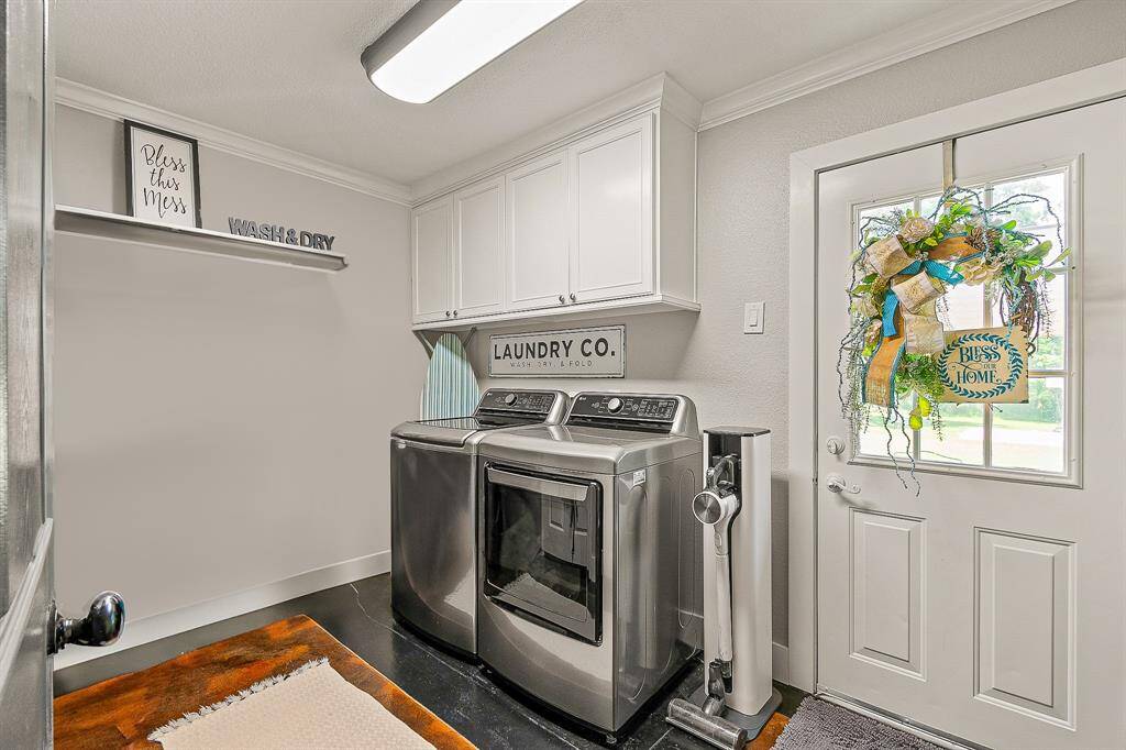 The laundry room has plenty natural light with white cabinets.