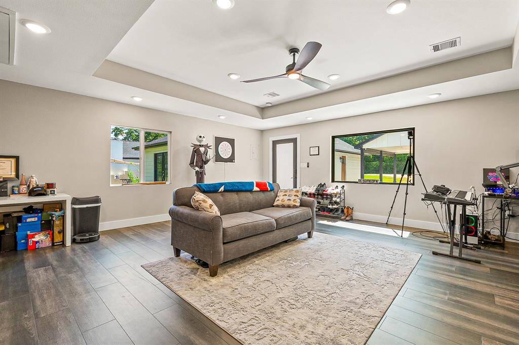 Bright and spacious Guest house living area with modern tray ceiling, recessed lighting, and a ceiling fan.