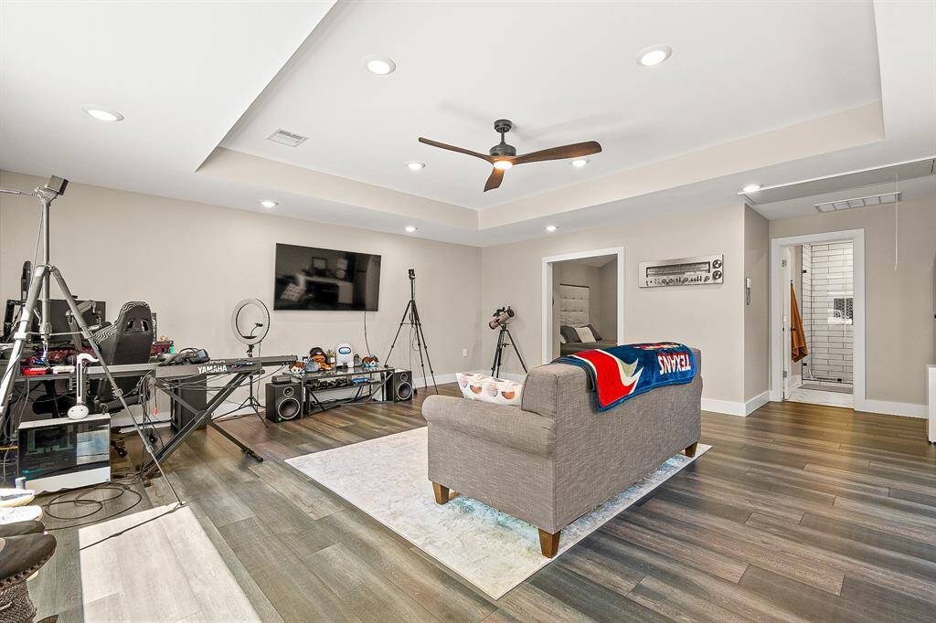 Bright and spacious Guest house living area with modern tray ceiling, recessed lighting, and a ceiling fan.