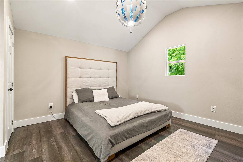 Guest house bedroom with vaulted ceiling, modern lighting, and a window for natural light.