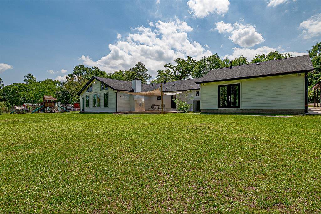 A modern single-story home with a spacious backyard, surrounded by greenery. The house features large windows and a patio area, perfect for outdoor activities and relaxation.