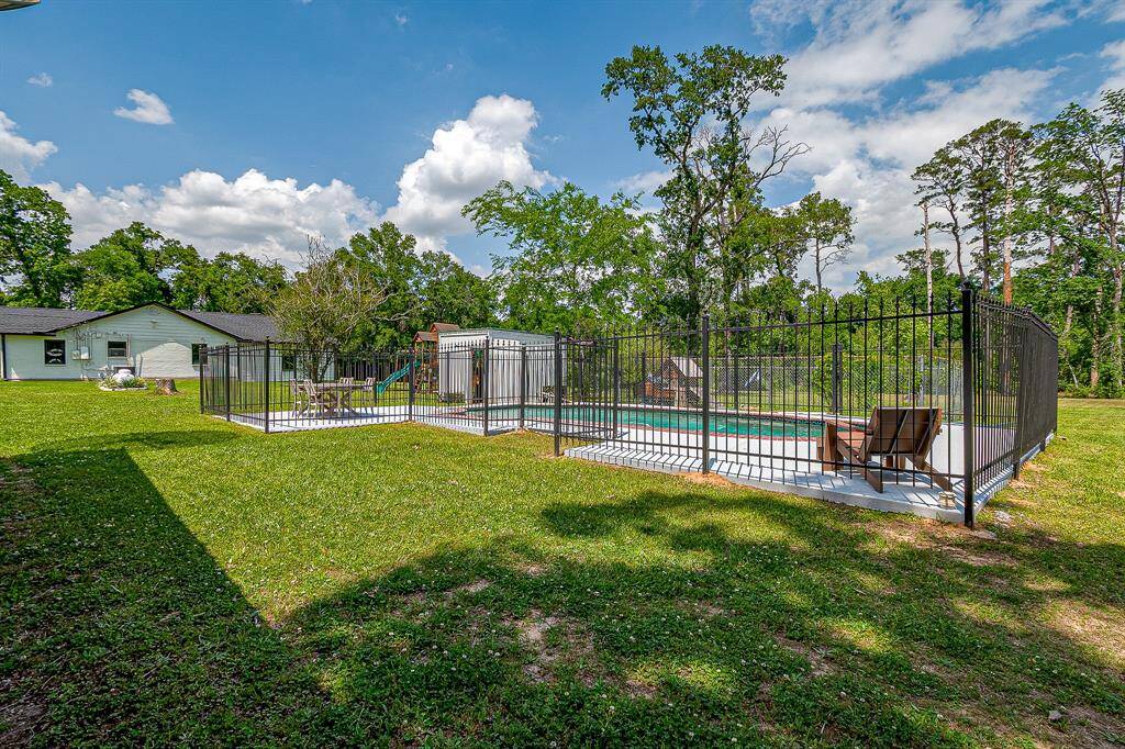 This photo showcases a spacious backyard featuring a fenced-in pool area surrounded by lush greenery and privacy. Ideal for outdoor relaxation and entertainment.