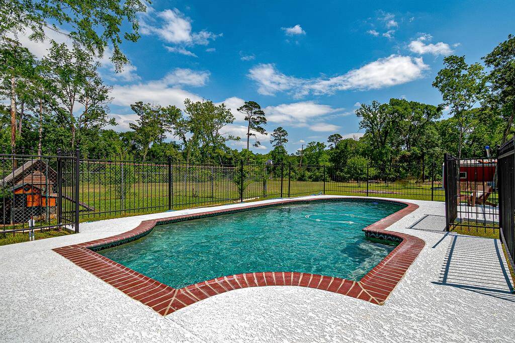 This photo features a private backyard with a fenced-in swimming pool, surrounded by lush greenery and mature trees, providing a serene and inviting outdoor space.