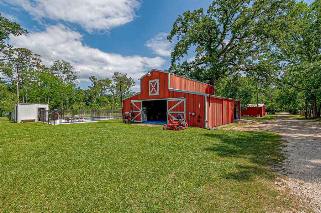 This property features a charming red pole barn with a classic design, nestled in lush greenery. Perfect for those seeking a rural lifestyle with ample outdoor space.