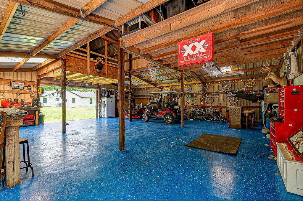 This spacious barn features a vibrant blue floor, ample storage, and workspace areas. It includes a loft and has plenty of room for vehicles and hobbies. Ideal for DIY enthusiasts.