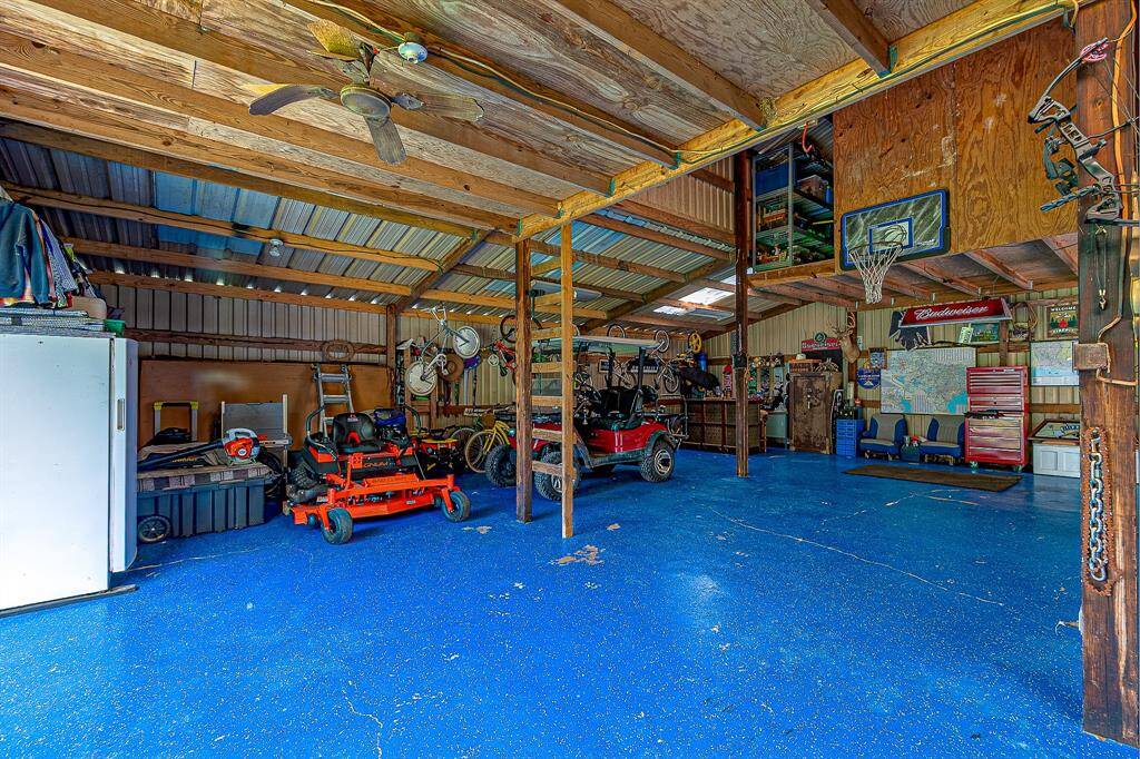 This spacious barn features a vibrant blue floor, ample storage, and workspace areas. It includes a loft and has plenty of room for vehicles and hobbies. Ideal for DIY enthusiasts.