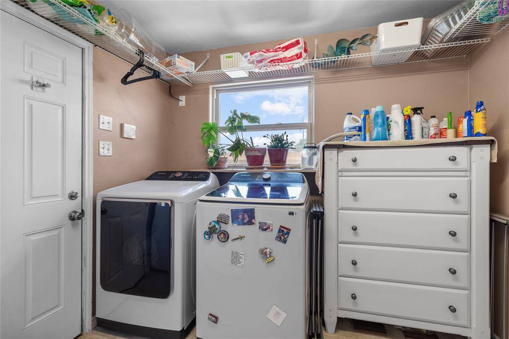 This photo shows a well-organized laundry room with a washer and dryer, ample shelving for storage, and a window providing natural light.