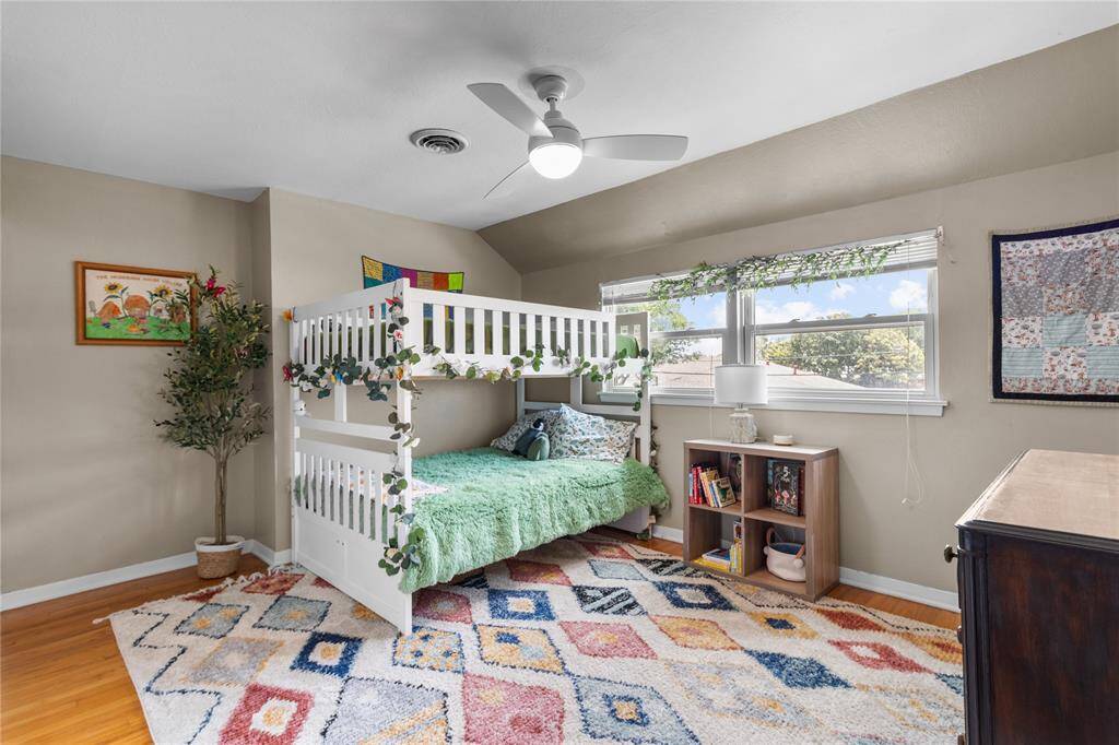 This cozy bedroom features ample natural light from two large windows. The room includes a new ceiling fan, creating a welcoming and functional space.