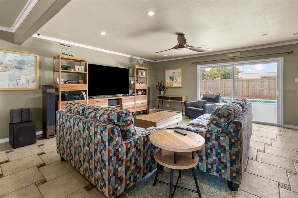 This spacious living room features stylish tile flooring. It has ample natural light from sliding glass doors that lead to a fenced backyard, creating a cozy and inviting atmosphere.