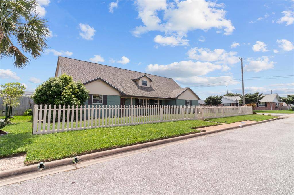 Charming single-story home with a gabled roof, surrounded by a white picket fence. Features a spacious front yard with manicured lawn and trees. Located in a quiet neighborhood, perfect for families.