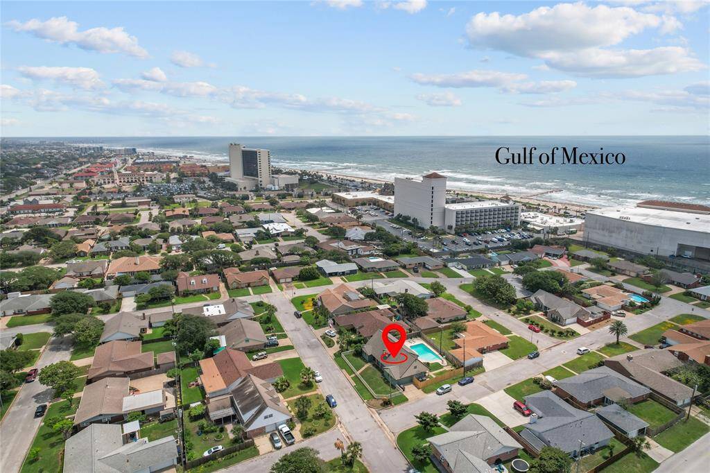 This aerial photo showcases a residential neighborhood near the Gulf of Mexico. The highlighted property features a pool and is situated in a community with close proximity to the beach, offering ocean views and easy access to local amenities.
