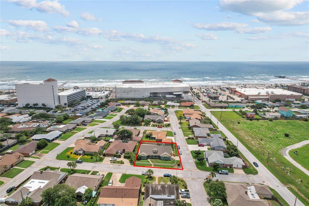 This aerial photo showcases a charming single-story home highlighted in red, nestled in a peaceful neighborhood. It's conveniently located near the beach, offering both tranquility and stunning ocean views. Ideal for those seeking coastal living with community amenities nearby.
