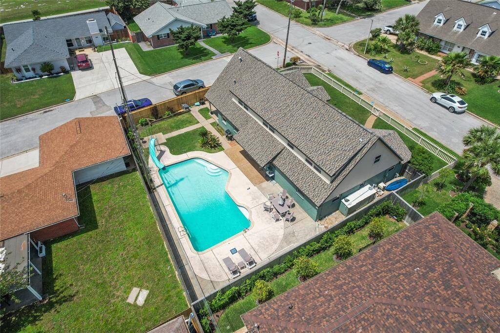This aerial photo showcases a well-maintained home with a large backyard featuring a swimming pool and patio area. The property is situated in a suburban neighborhood with well-kept lawns and nearby houses.
