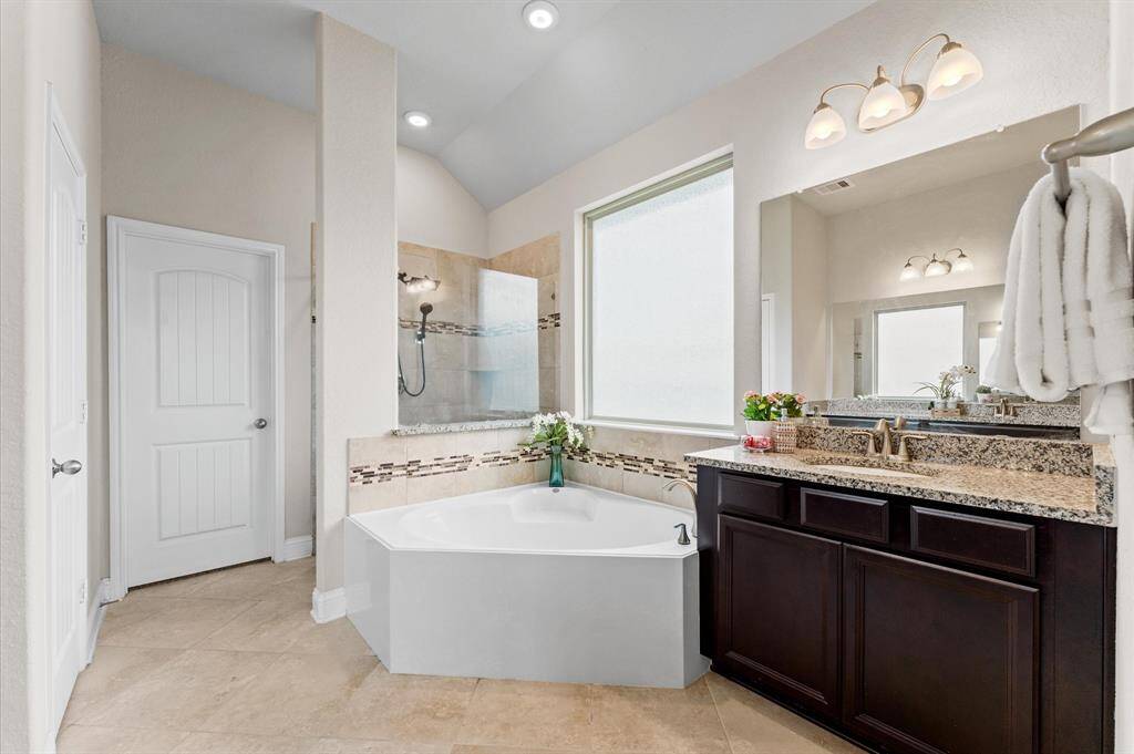 Step into a spa-like en suite bath, where elegance meets functionality. A luxurious garden tub sits by a window, inviting you to soak in the natural light.
