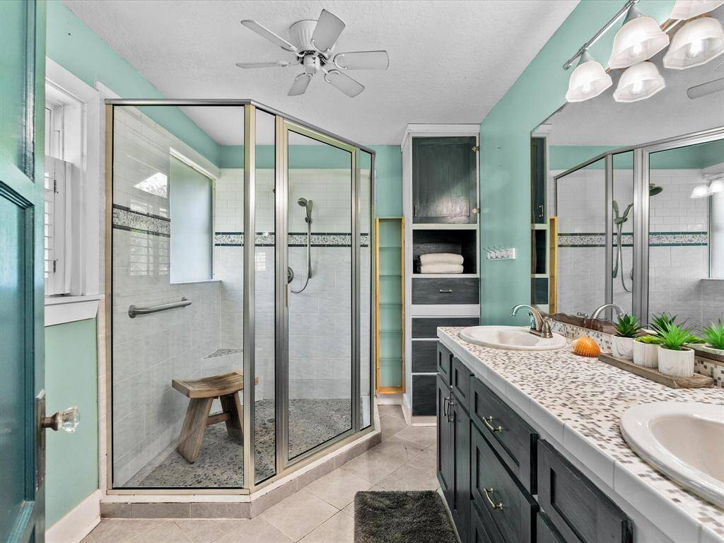 Primary bathroom with double sinks, large shower, & lots of shelves.