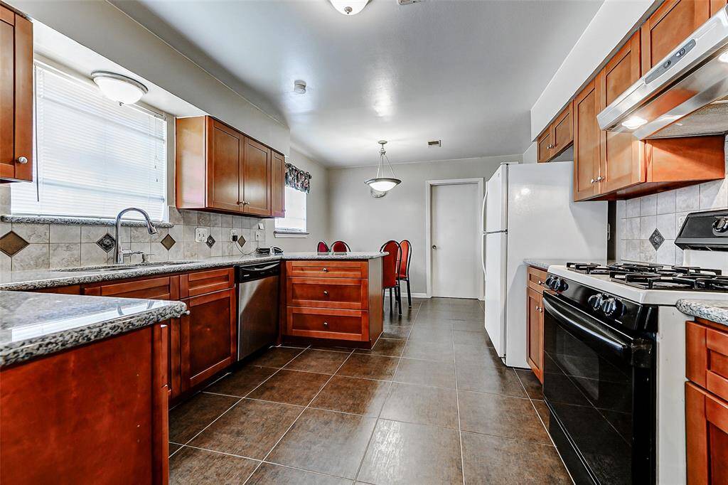 Tastefully updated kitchen featuring granite counters, modern cabinetry, and stainless steel appliances. A cozy breakfast nook sits tucked at the end, perfect for casual dining or morning coffee with plenty of natural light.
