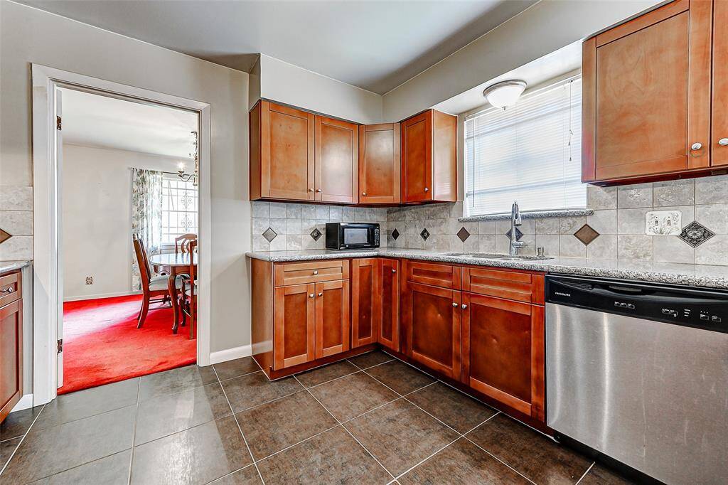 Spacious, thoughtfully designed kitchen opens toward the dining room, creating a welcoming atmosphere for daily living or entertaining. Crisp tile floors, granite counters, and plenty of cabinetry make this a dream space to cook and gather.