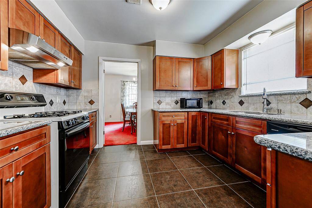 Updated kitchen with granite countertops, modern cabinetry, and an efficient layout perfect for cooking and entertaining. Natural light pours in, highlighting the spacious feel and stylish tile backsplash. Ideal connection to the dining room for easy flow.